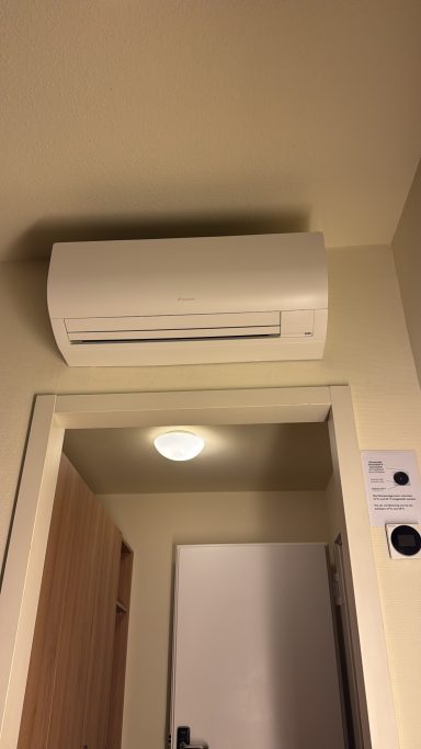 Wandklimaanlage über einer Tür in einem hellen Raum montiert.