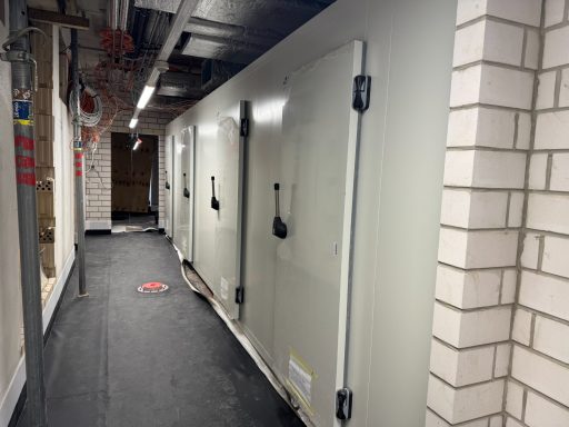 Korridor mit mehreren großen, geschlossenen Kühlcontainern an der Wand.