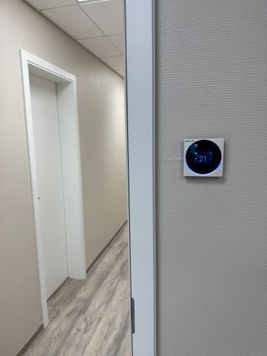 Klimaanlage oder Thermostat an einer Wand, mit einer Tür im Hintergrund.